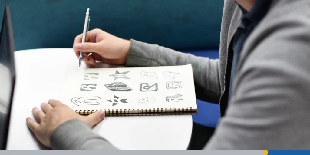 Person designing logos on a notebook. Handmade logo creation process.