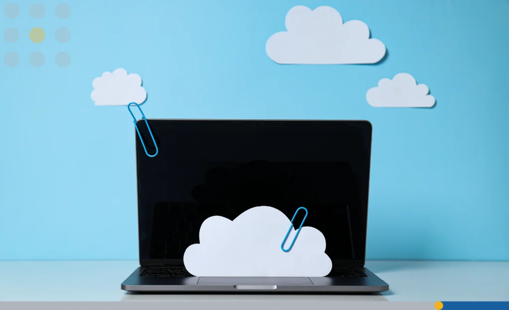 Laptop with paper clouds on a blue background.