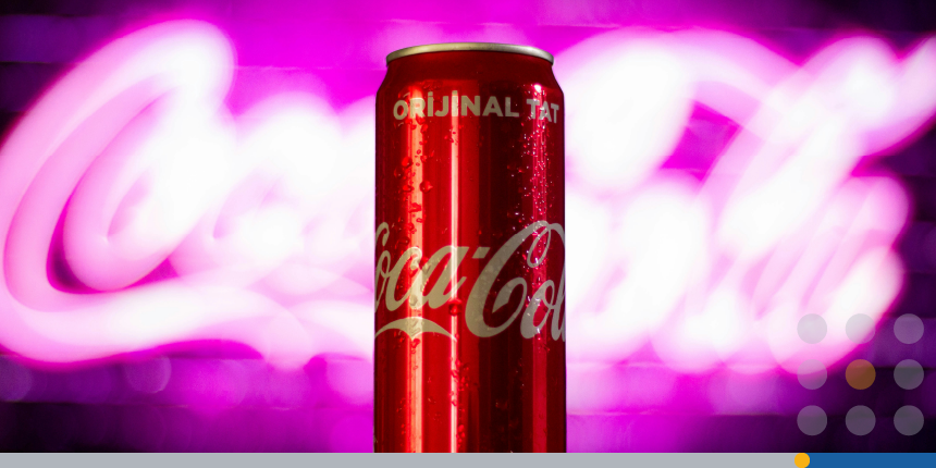 A can of Coco-Cola with Coca-Cola’s brand logo behind it in neon light