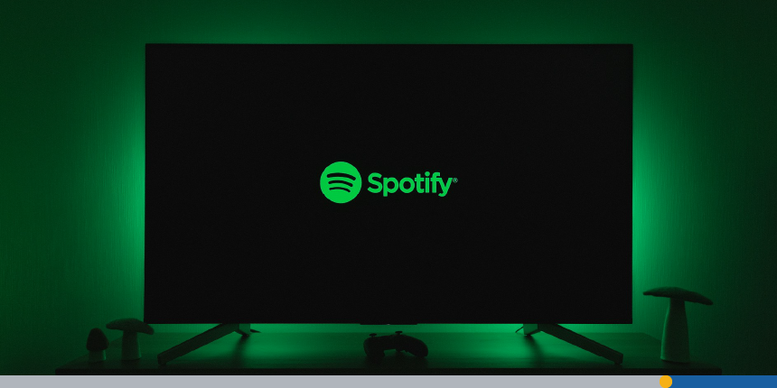 Spotify's famous logo font is displayed on a large television screen.