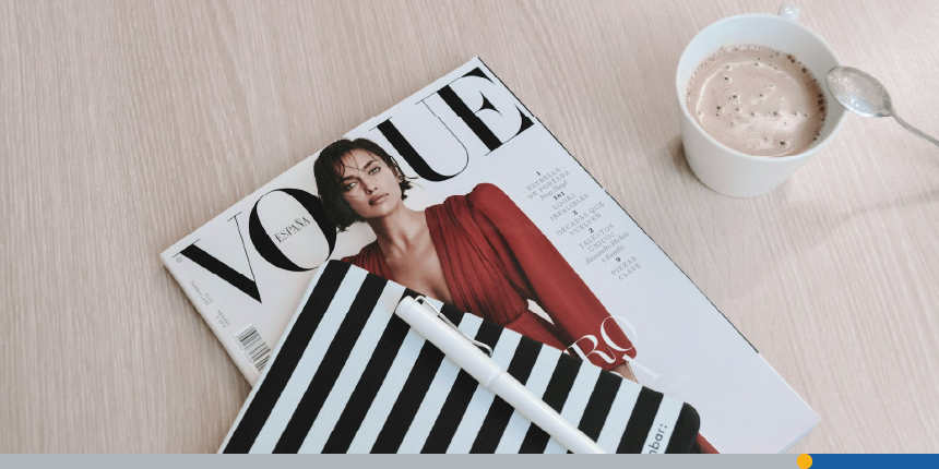 A copy of Vogue magazine sits on a table top displaying decorative elements such as logo design.