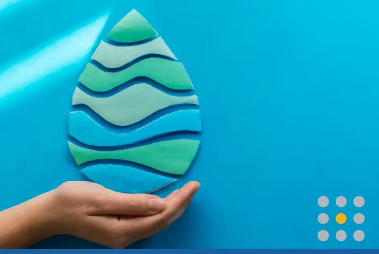 View of woman hands holding paper cut water drop on a blue background