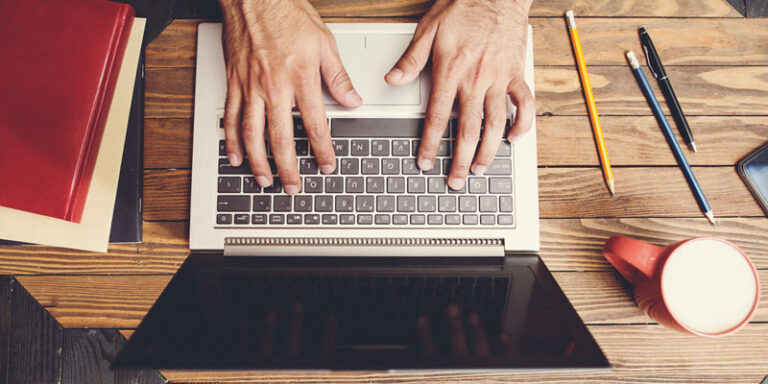 man typing on laptop at desk