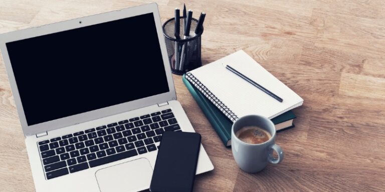 laptop, phone, pens and notepad on a desk